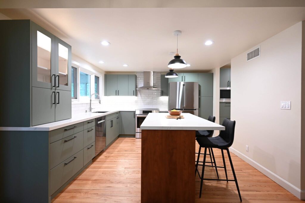 Thousand Oaks Kitchen Remodels Kitchen remodeling project: Modern sage green flat-panel kitchen with white quartz island, walnut base, and hardwood floors in Thousand Oaks by RnD Builders Inc
