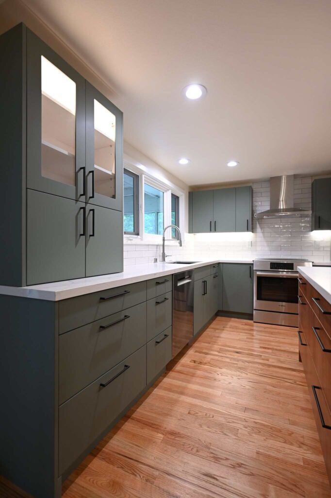 Modern sage green flat-panel kitchen with white quartz countertops and stainless steel appliances in Thousand Oaks by RnD Builders Inc